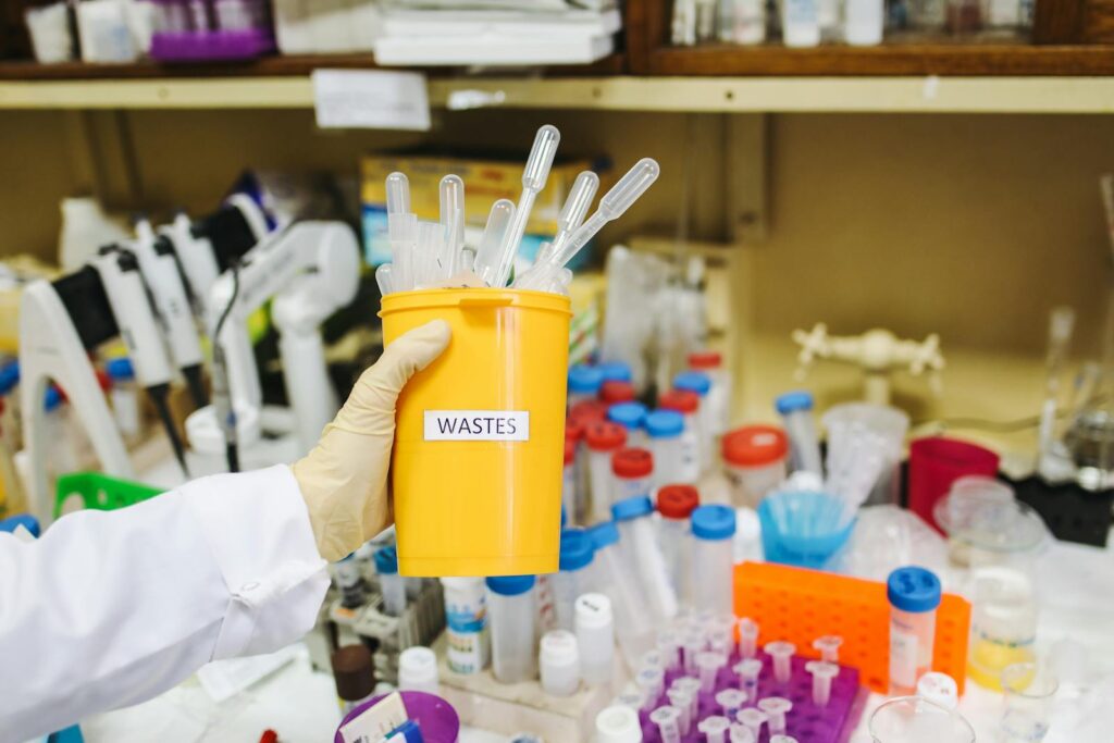 Scientist handling laboratory waste in a controlled environment, focusing on safety and cleanliness.