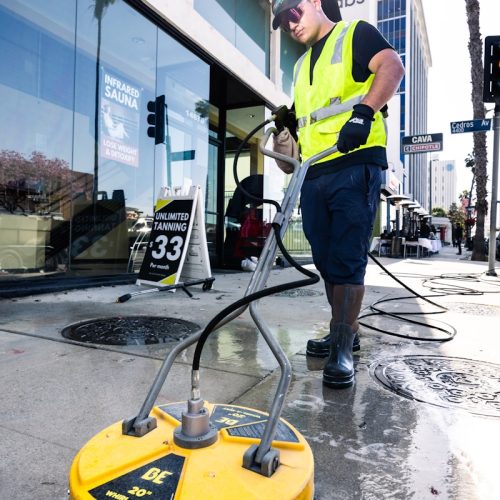 a man in a yellow vest is cleaning the street